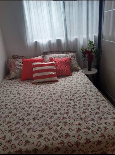 - un lit avec des oreillers rouges et blancs dans une chambre dans l'établissement Casa Aeroporto Maceió Palmeiras, à Maceió