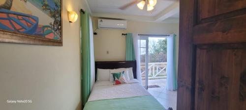 a bedroom with a bed and a door to a porch at Faith's Villa Tobago in Diamond