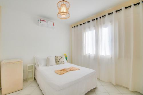 a white bedroom with a bed and a window at Elsi Pousada in Búzios