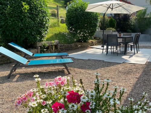 a blue bench in a garden with flowers and an umbrella at L’ Annexe in Chariez