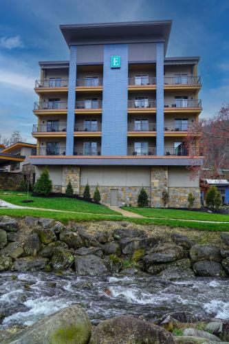 a building with a sign on it next to a river at Embassy Suites By Hilton Gatlinburg Resort in Gatlinburg
