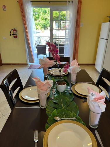 a dining room table with plates and flowers on it at Faith's Villa Tobago in Diamond