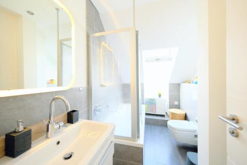 a white bathroom with a sink and a toilet at HappyBnB - Stilvolles, naturgelegenes Apartment mit Blick auf den Mittellandkanal und die Wasserstadt Hannover - Kamin, Parken und Spielplatz in Hannover