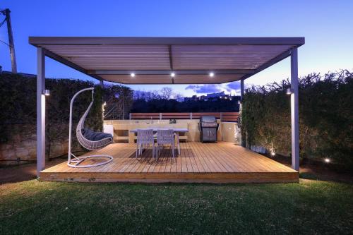 eine Terrasse mit einem Grill, einem Tisch und Stühlen in der Unterkunft Glaros Casa Verde - Cozy flat with Garden near Beach in Kato Daratso