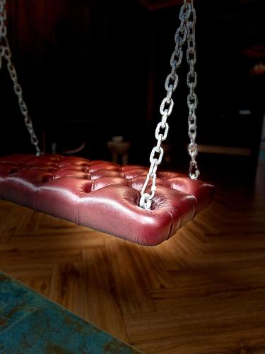 a red leather seat on a chain swing at ALL - Amberstone Lux Loft in Klaipėda