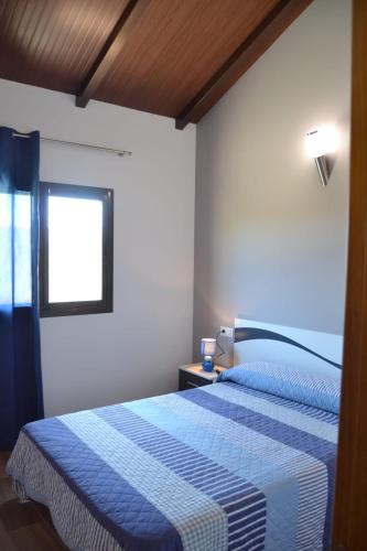 a bedroom with a blue and white bed with a window at CHALET SOLYMAR in Conil de la Frontera