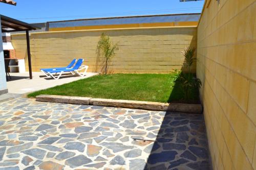 a blue chair sitting on a patio with a lawn at CHALET SOLYMAR in Conil de la Frontera
