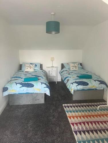 a bedroom with two beds and a table with a lamp at Annie's Hideaway in Chapel Saint Leonards