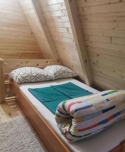 ein Bett in einer Holzhütte mit einer Decke darauf in der Unterkunft Konak kod Tose in Banja Luka