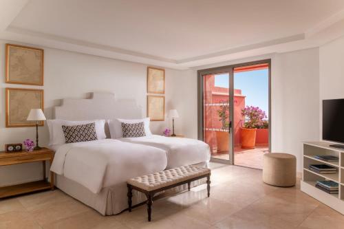 a white bedroom with a large bed and a television at The Ritz-Carlton Tenerife, Abama in Guía de Isora