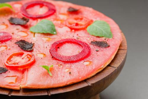 a pizza with tomatoes and basil on a wooden plate at The Ritz-Carlton Tenerife, Abama in Guía de Isora