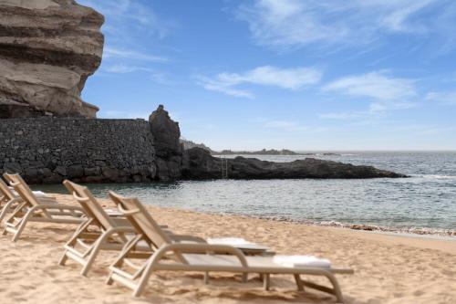 two lounge chairs on a sandy beach near the water at The Ritz-Carlton Tenerife, Abama in Guía de Isora