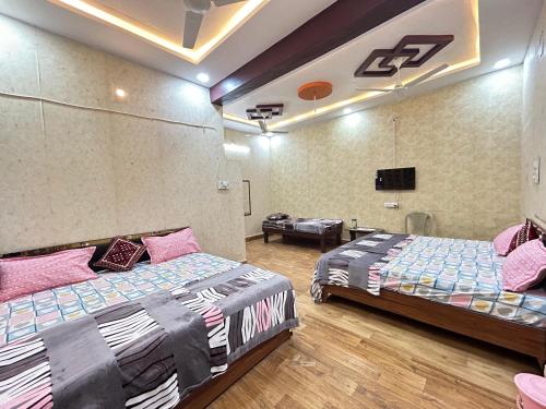 1 dormitorio con 2 camas y TV de pantalla plana en Ashirwad Holiday Homes, en Ujjain