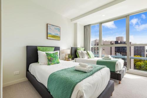 a bedroom with two beds and a large window at Brand New Luxe 3-Bed Apartment In Aotea Square in Auckland