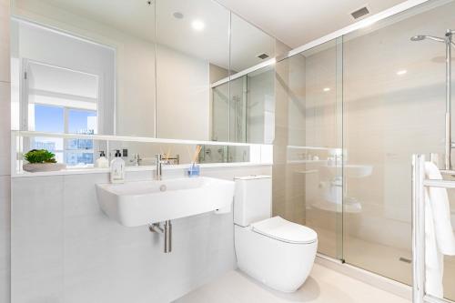 a white bathroom with a sink and a toilet at Brand New Luxe 3-Bed Apartment In Aotea Square in Auckland