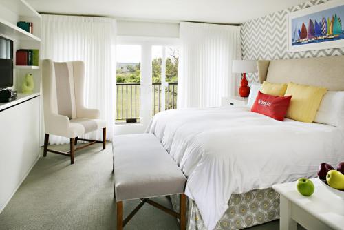 a white bedroom with a large bed and a chair at Winnetu Oceanside Resort at South Beach in Edgartown