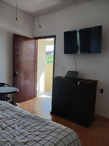 a bedroom with a bed and a flat screen tv at POSADA del MAR in Puerto Escondido