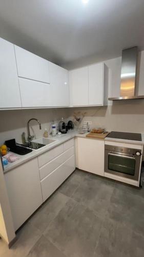 une cuisine avec des armoires blanches et un évier dans l'établissement Appartement sur la plage, à Fos-sur-Mer