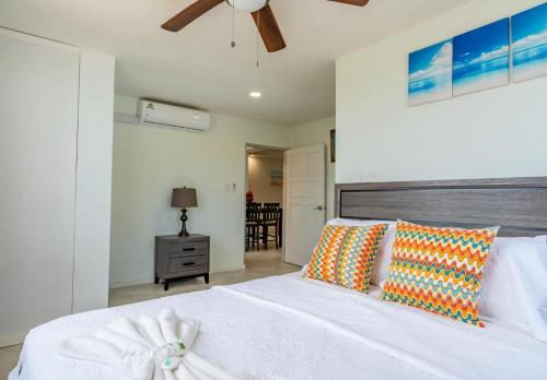 a bedroom with a white bed and a ceiling fan at Faith's Villa Tobago in Diamond