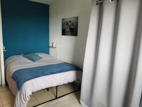 une chambre avec un lit avec un mur bleu dans l'établissement COSY EVASION, à Blaye