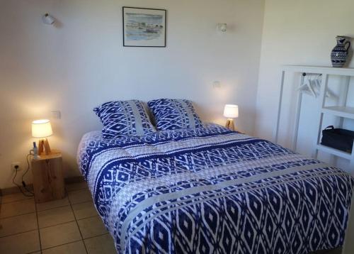 - un lit bleu et blanc dans une chambre avec deux lampes dans l'établissement Gîte Océanite - Kerlouan, à Kerlouan