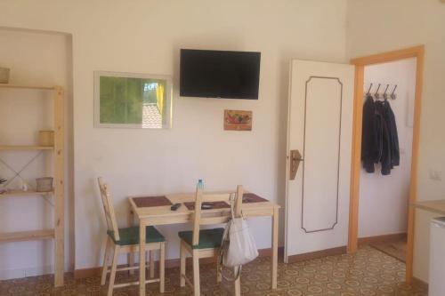 Habitación con mesa, sillas y TV en la pared. en Casa Rosa sopra la Costiera, en San Lazzaro Agerola