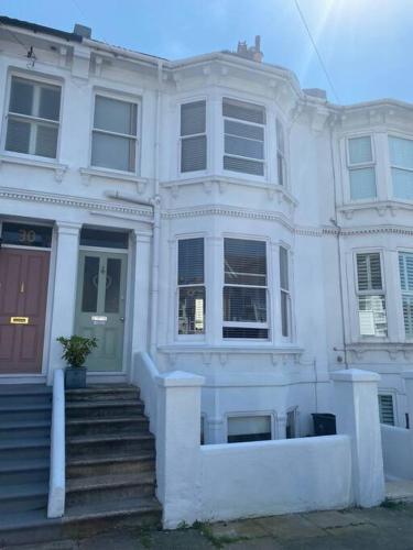 a white house with stairs in front of it at Poets Place - lovely 4 bedroom townhouse with garden in Brighton & Hove