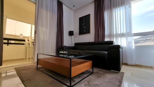 a living room with a black couch and a table at Appartement marina agadir in Agadir