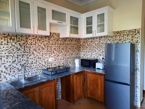 a kitchen with white cabinets and a refrigerator at Ellyz Home Stay in Moshi