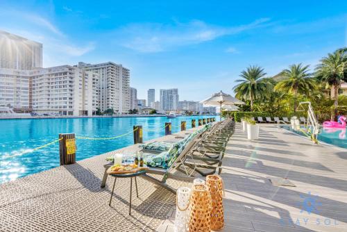 a pool at a resort with chairs and a table at Upper Beachwalk Condo Amazing Balcony View in Hallandale Beach