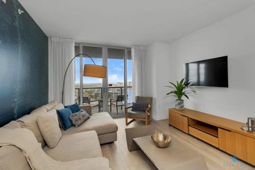 a living room with a couch and a tv at Upper Beachwalk Condo Amazing Balcony View in Hallandale Beach