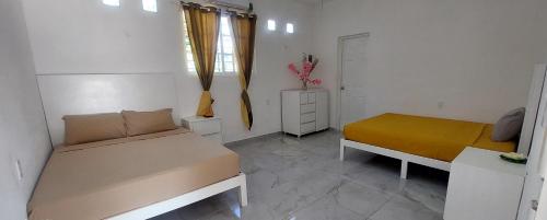 a small bedroom with two beds and a window at Casa frida bacalar in Bacalar