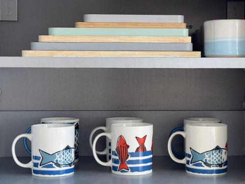 a row of coffee mugs sitting on a shelf at Sandy Toes - awesome beach view and access in Ventnor