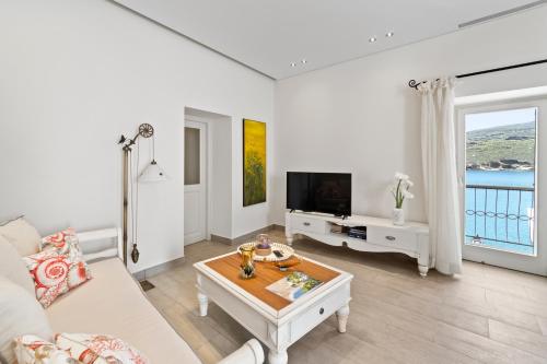 a white living room with a couch and a tv at Seafront, Luxury 2-BDR Townhouse in Andros