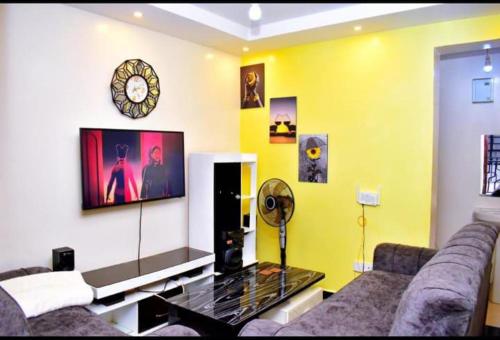uma sala de estar com um sofá e um relógio na parede em Blissfulgetaway em Thika
