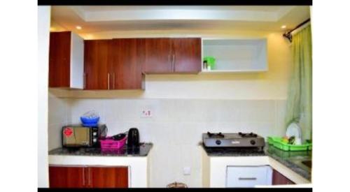 uma pequena cozinha com armários de madeira e um fogão em Blissfulgetaway em Thika