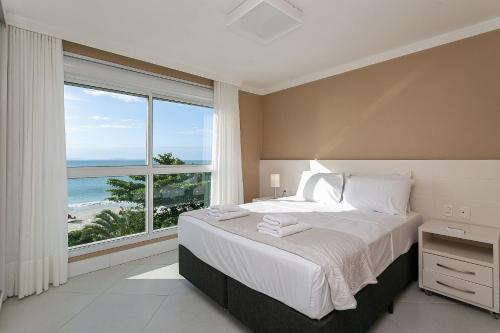 um quarto com uma cama grande e uma janela grande em Varanda com Churrasqueira e Vista MAR #CHA06 em Florianópolis