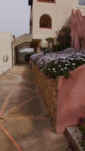 a building with a stone wall with flowers on it at Casa vacanze con terrazza panoramica vista mare in Portu Maga