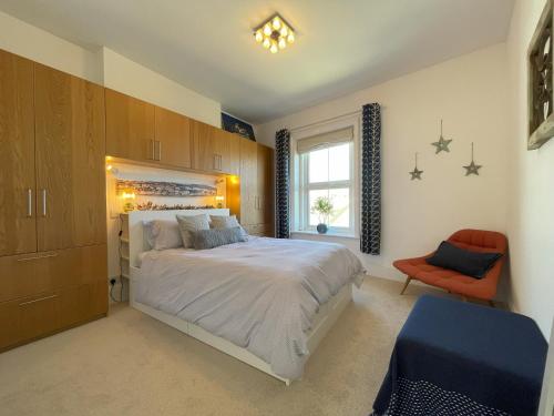 1 dormitorio con 1 cama grande y 1 silla naranja en Sandy Toes - awesome beach view and access, en Ventnor