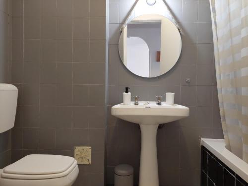 een badkamer met een wastafel, een toilet en een spiegel bij Alltravel pátio da rocha in Portimão