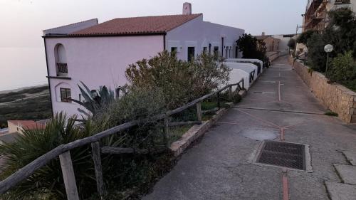a street with a row of white buildings and a fence at Casa vacanze con terrazza panoramica vista mare in Portu Maga