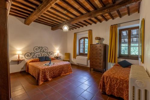 a bedroom with two beds and two windows at Villa Palazzo Bello con piscina e AC - Cetona in Cetona