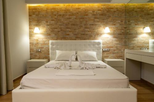 a white bed in a room with a brick wall at Aqua Mare Luxury Apartments in Paralia Katerinis