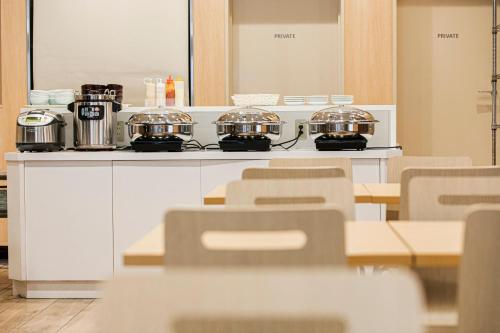 a kitchen with a table and chairs with pots and pans at Smile Hotel Hakataekimae in Fukuoka