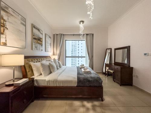 a bedroom with a bed and a desk and a window at JBR Beach, The Walk, 1-BDR with pool view in Dubai