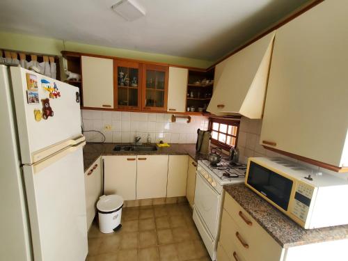 a kitchen with a white refrigerator and a sink at CASA BARRIO SOMISA in San Nicolás de los Arroyos