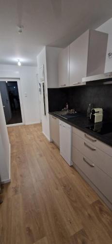 une cuisine avec des armoires blanches et un plancher en bois dans l'établissement Studio avec terrasse hyper centre Colmar, à Colmar