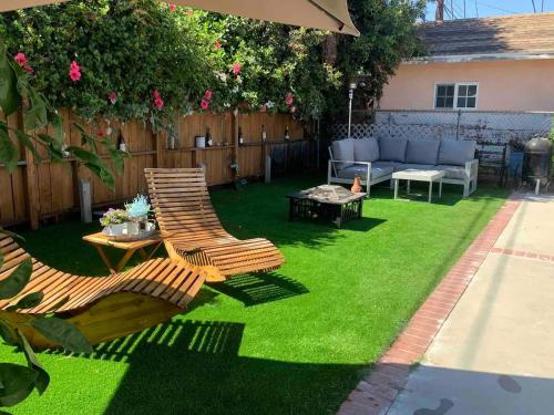 a backyard with green grass and two chairs and a table at Cozy 1-bedroom in a Brazilian home in Los Angeles