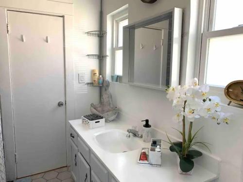 a bathroom with a sink and a vase of flowers at Cozy 1-bedroom in a Brazilian home in Los Angeles