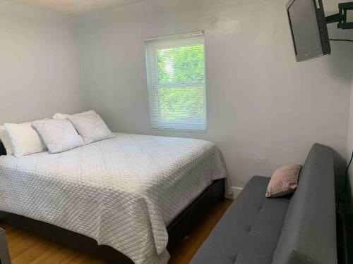 1 dormitorio con cama, ventana y sofá en Cozy 1-bedroom in a Brazilian home, en Los Ángeles
